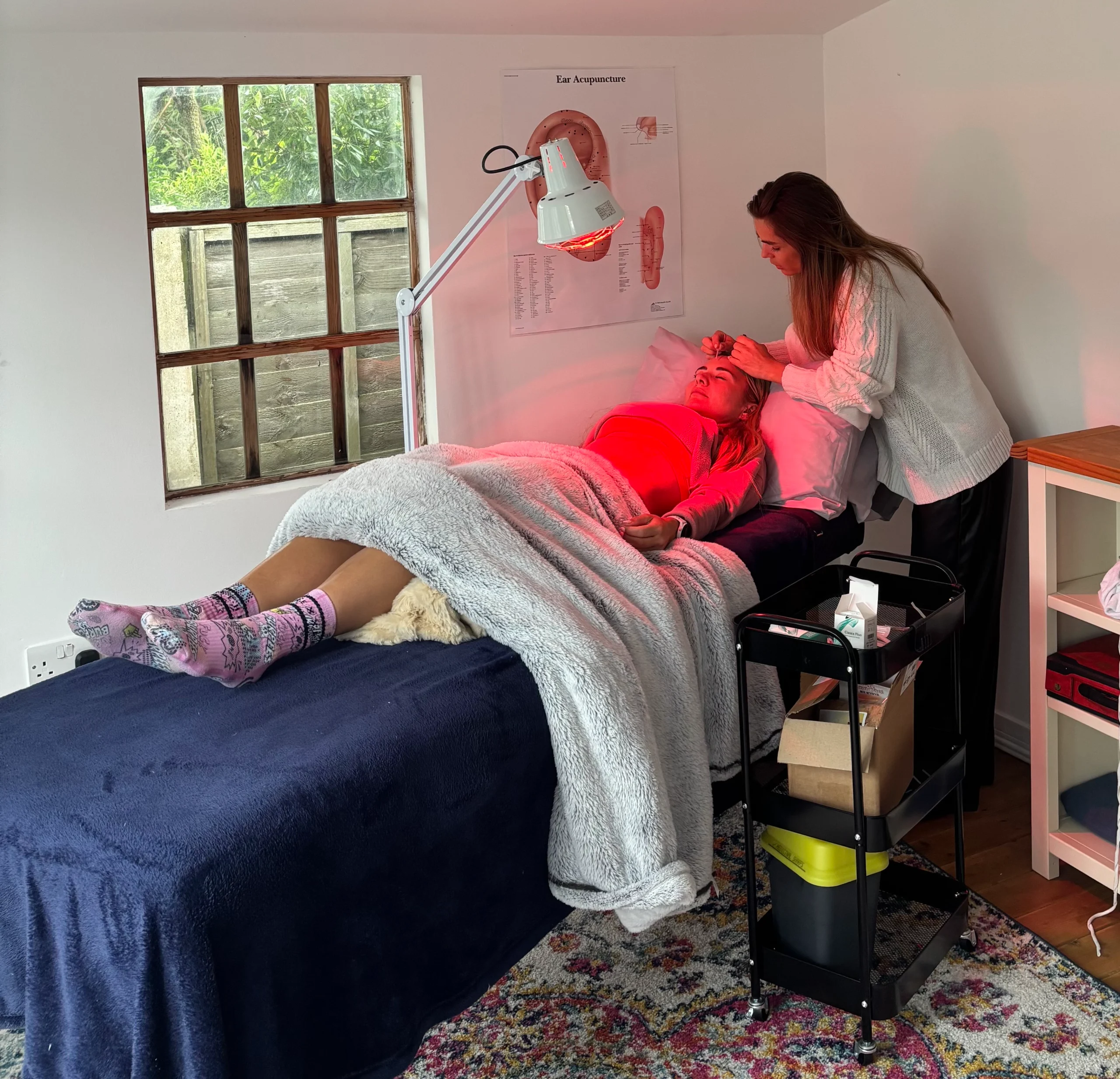 Acupuncture treatment in a cozy room – Practitioner treating a patient with acupuncture needles in a warmly decorated room.