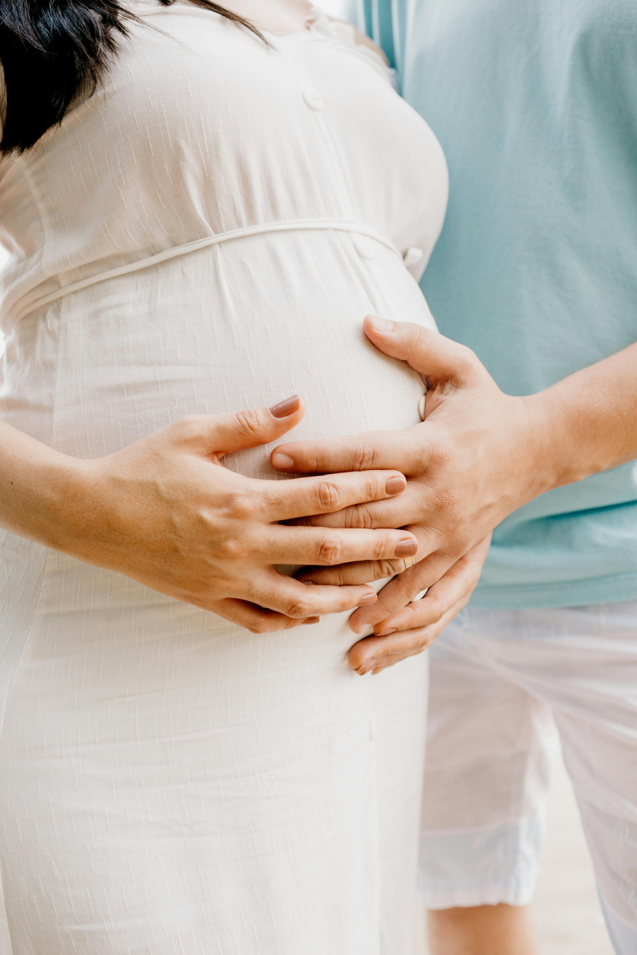 Pregnant woman receiving acupuncture – Close-up of hands applying acupuncture needles to a pregnant woman's belly.